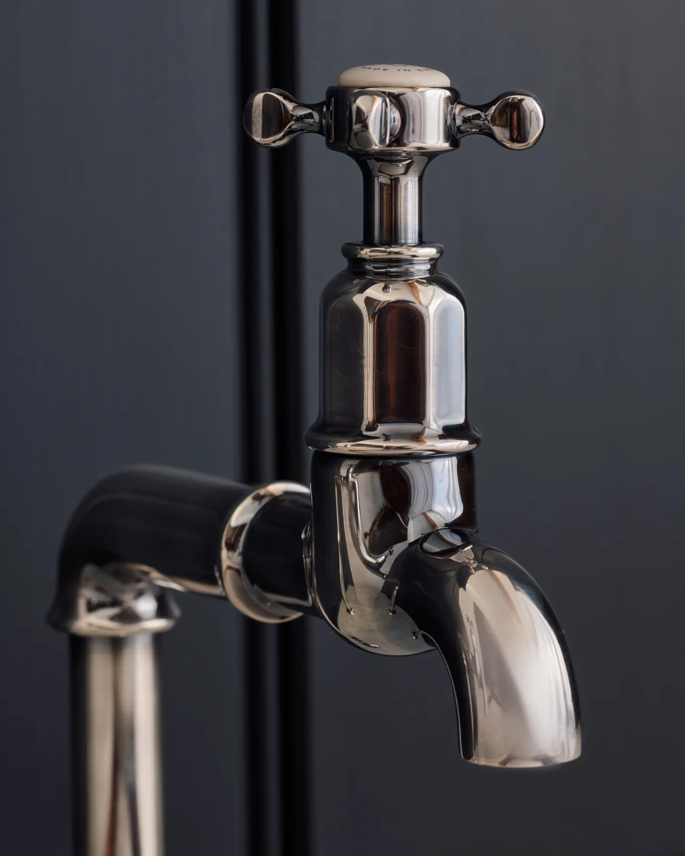 A close-up view of the head of a traditional-style tarnished silver bibcock tap with a crosshead handle.